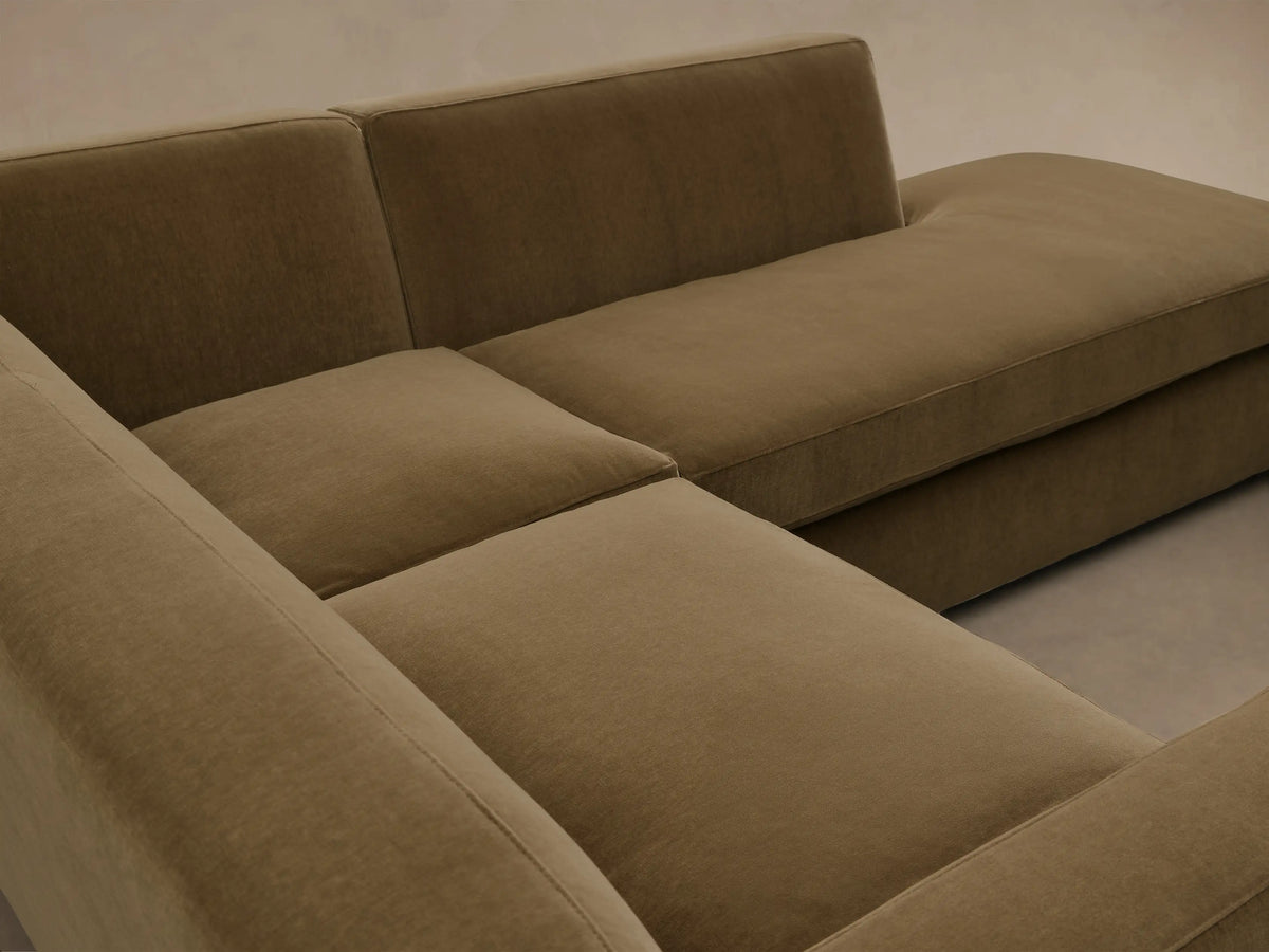 Front view of the Olive Bronte Two-Piece Bumper Chaise Sectional, an L-shaped sofa with thick cushions and dark wood feet.