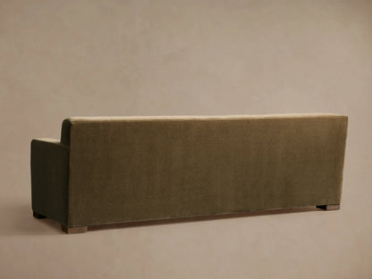 Rear view of an olive green Bronte Bench-Seat Sofa, featuring a low back, a partial left arm, and dark wooden block feet.