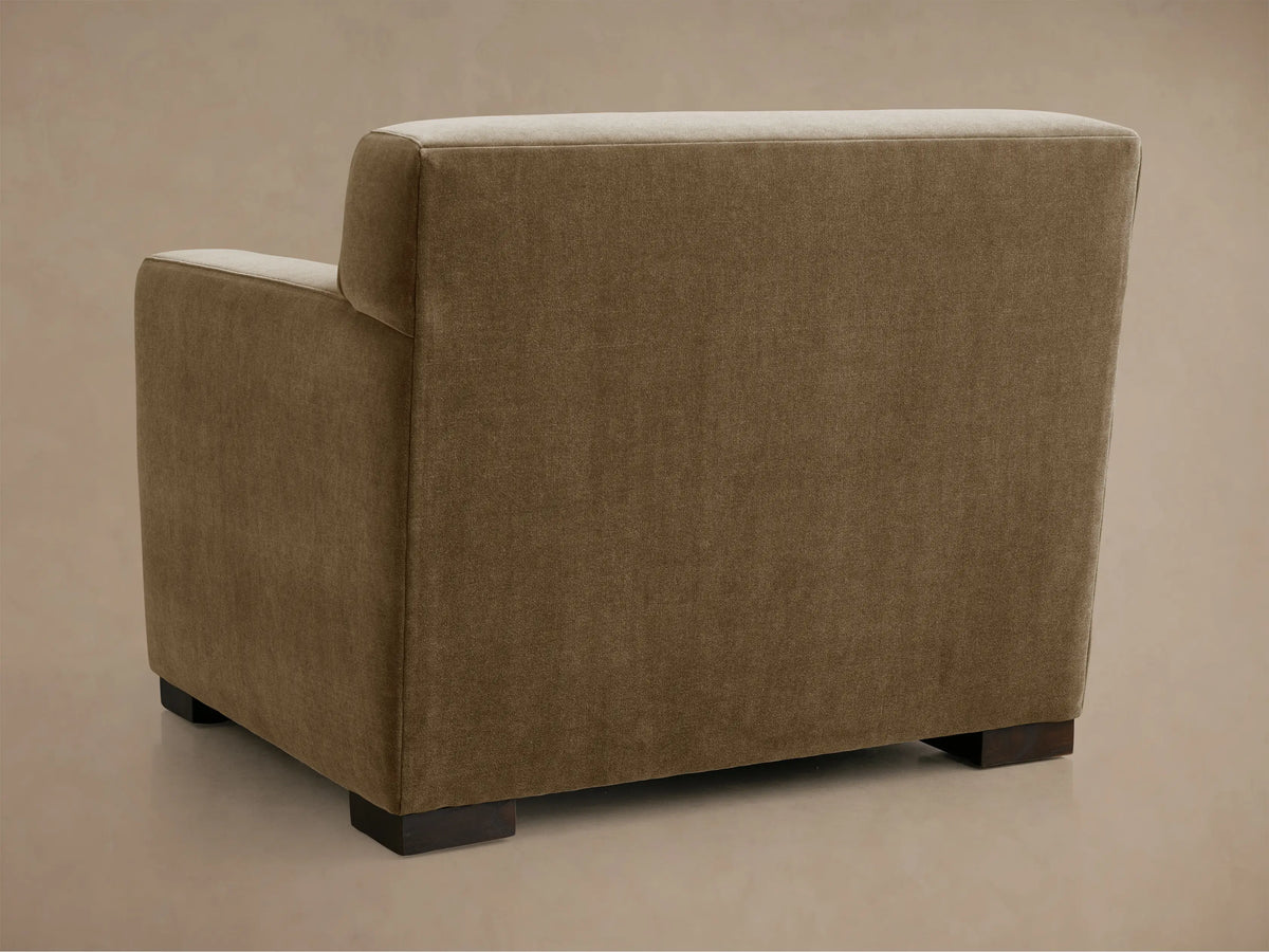 Close-up of Bronte Chair, showing its textured neutral beige upholstery on the seat, armrests, and back cushion, angled view.