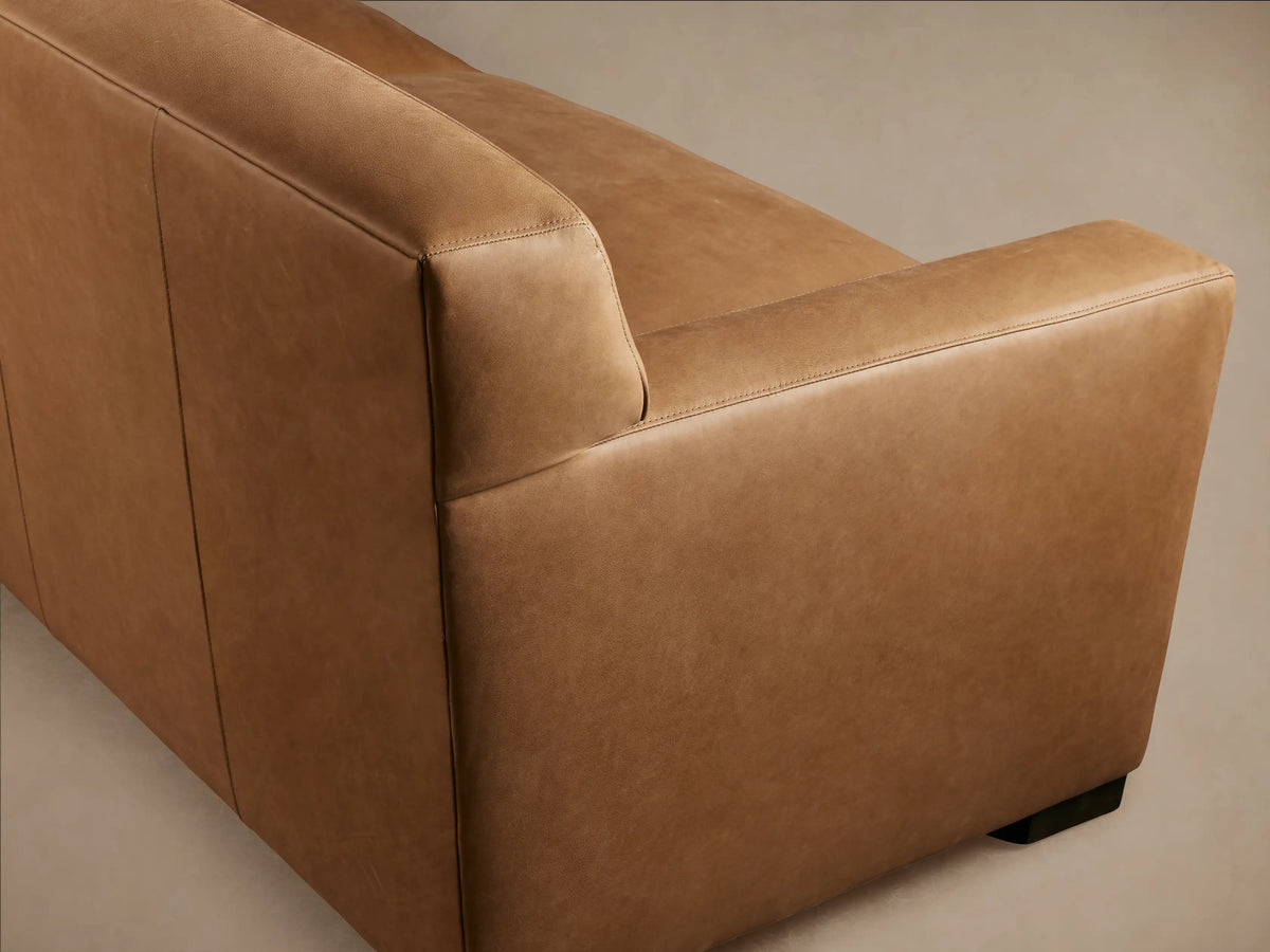 Bronte Leather Sofa in brown leather with a sleek, modern design. It features cushioned seats, wide armrests, and a low backrest.