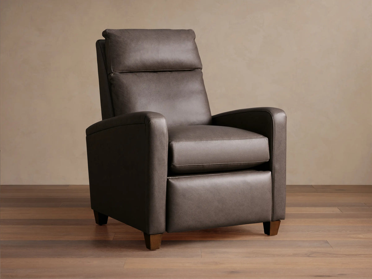 Colfax Leather Motion Recliner, dark taupe leather, upright, with comfortable padded headrest & wood feet, on wood floor.