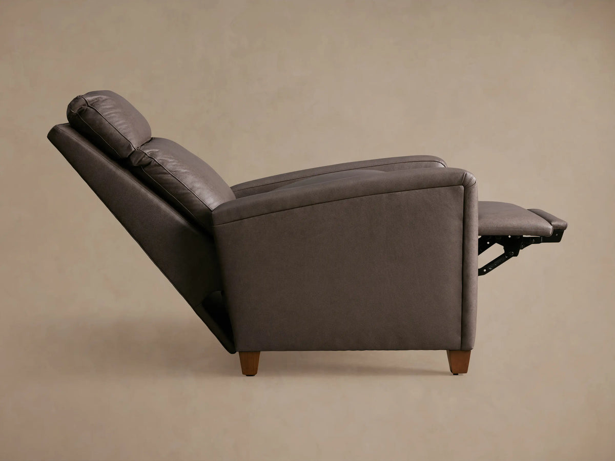 Dark brown Colfax Leather Motion Recliner, slightly angled, with the footrest partially extended, against a light brown wall.