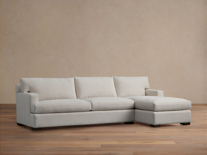 Zarevium Dune light off-white two-piece chaise sectional on wood floor, tan wall backdrop.