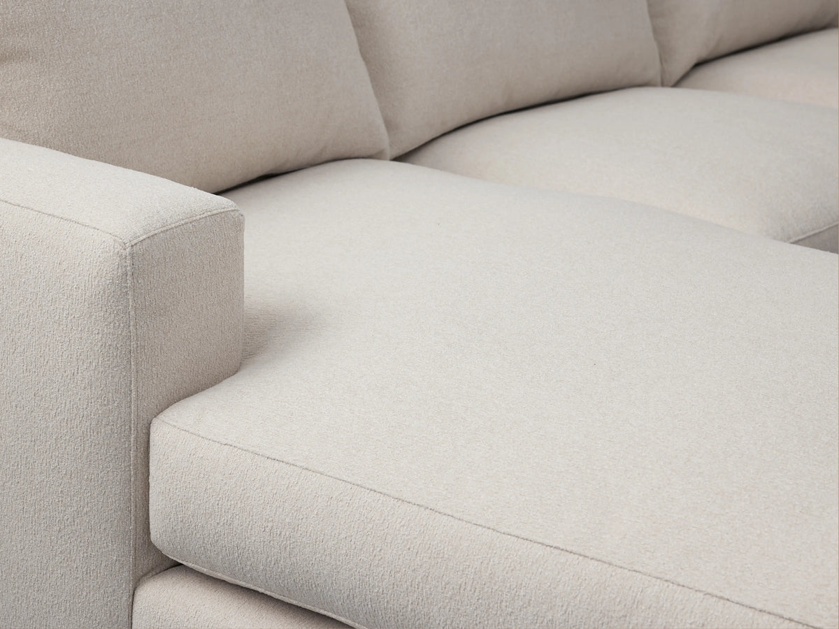Zarevium Dune Two-Piece Chaise Sectional in light cream fabric, chaise on left, on a wood floor against a beige wall.