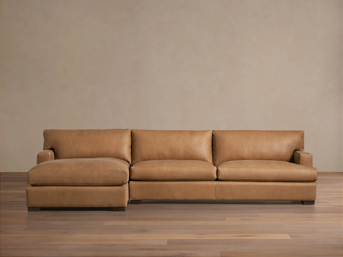 Dune Leather Two Piece Chaise Sectional in caramel brown leather, featuring left chaise, three seat cushions, and subtle stitching details.