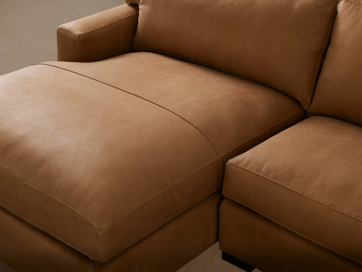 Dune Leather Two Piece Chaise Sectional in light brown leather, with a left-facing chaise lounge and three-seat cushions, on a hardwood floor.