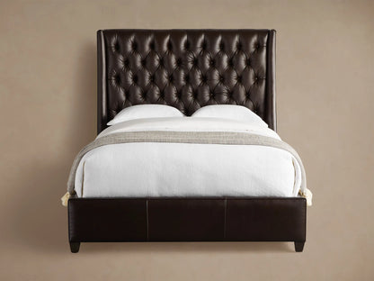 Devereaux Leather Tufted Bed in dark brown leather with a deeply tufted headboard, white bedding, and gray throw on wood floor.