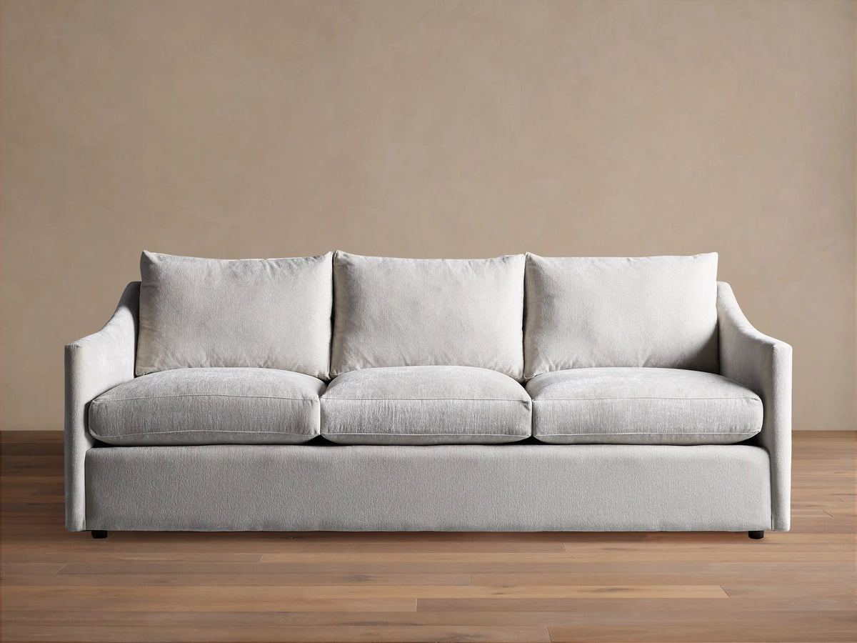 Light grey Branson Sofa with 3 seat & 3 back cushions, wide sloped arms, and a skirted base, shown front-on.