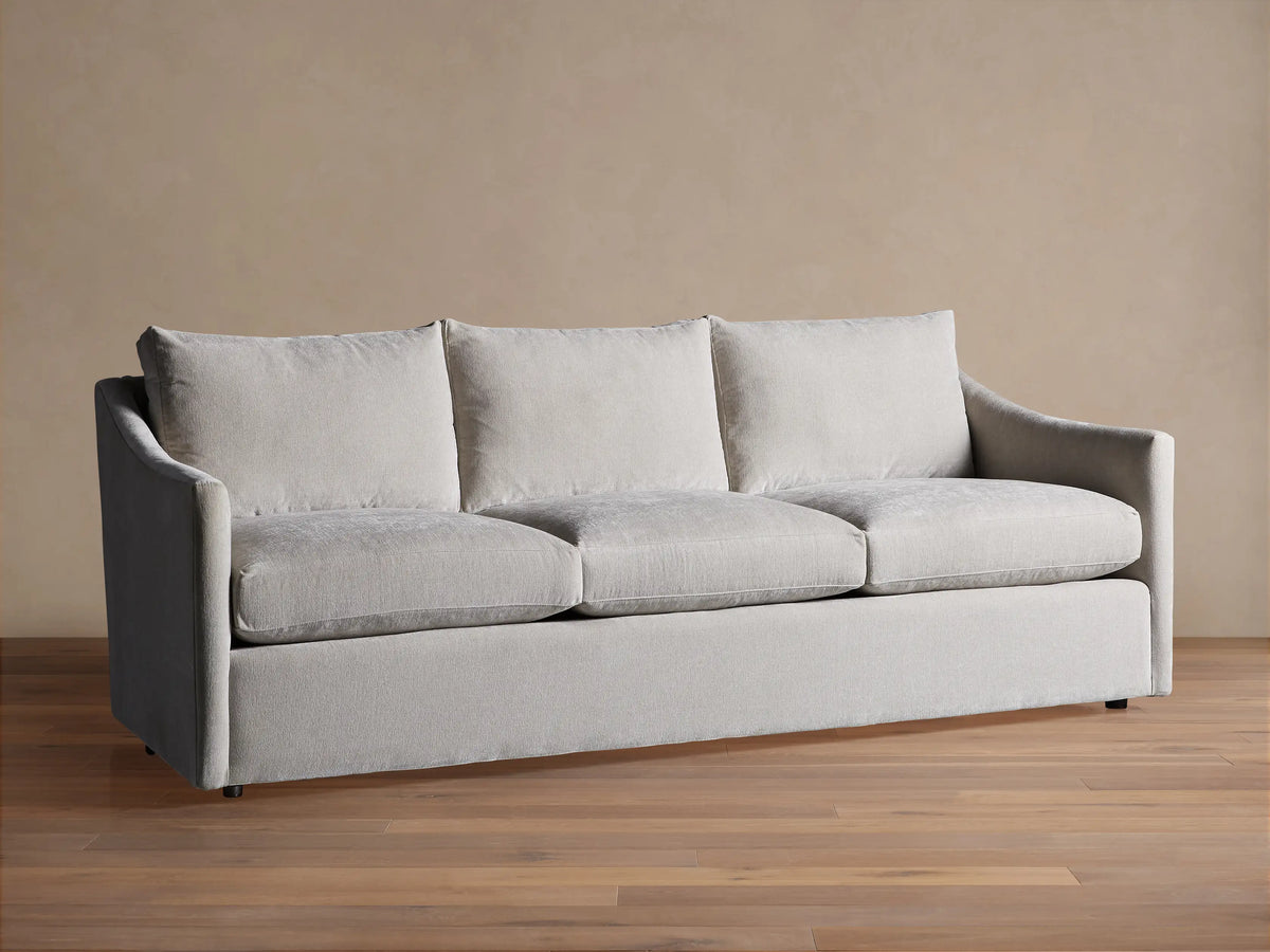 Light grey Branson Sofa with 3 seat & 3 back cushions, wide sloped arms, and a skirted base, shown front-on.