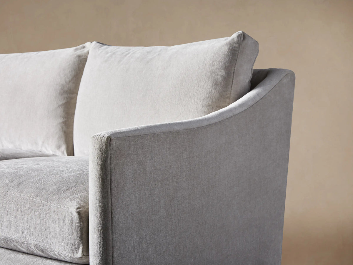 Branson Sofa, light gray fabric, 3-seater, with soft cushions, gently curved arms, and a skirted base, on a wood floor.