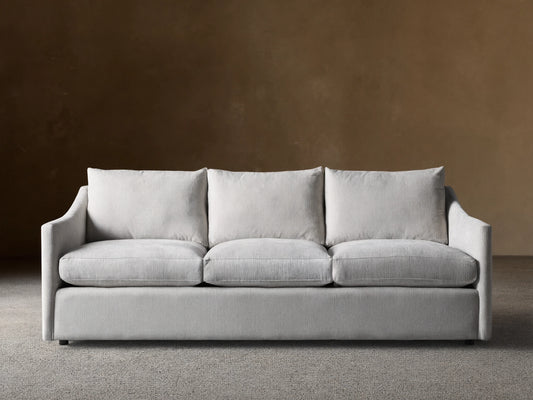 Light grey Branson Sofa with 3 seat & 3 back cushions, wide sloped arms, and a skirted base, shown front-on.