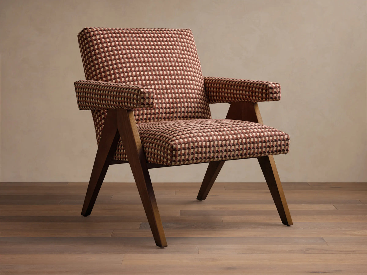 Front view of the brown and beige upholstered Elias Chair, with a geometric checkerboard pattern, and dark wood exposed arms and tapered legs.