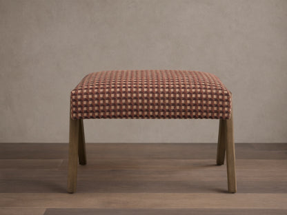 Front view of the Elias Ottoman with reddish-brown, light brown, and dark brown geometric cube pattern upholstery and light wood legs.