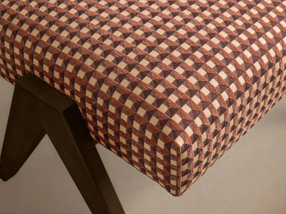 Close-up of the Elias Ottoman, showing a brown and beige geometric checkered upholstery with dark wooden legs.