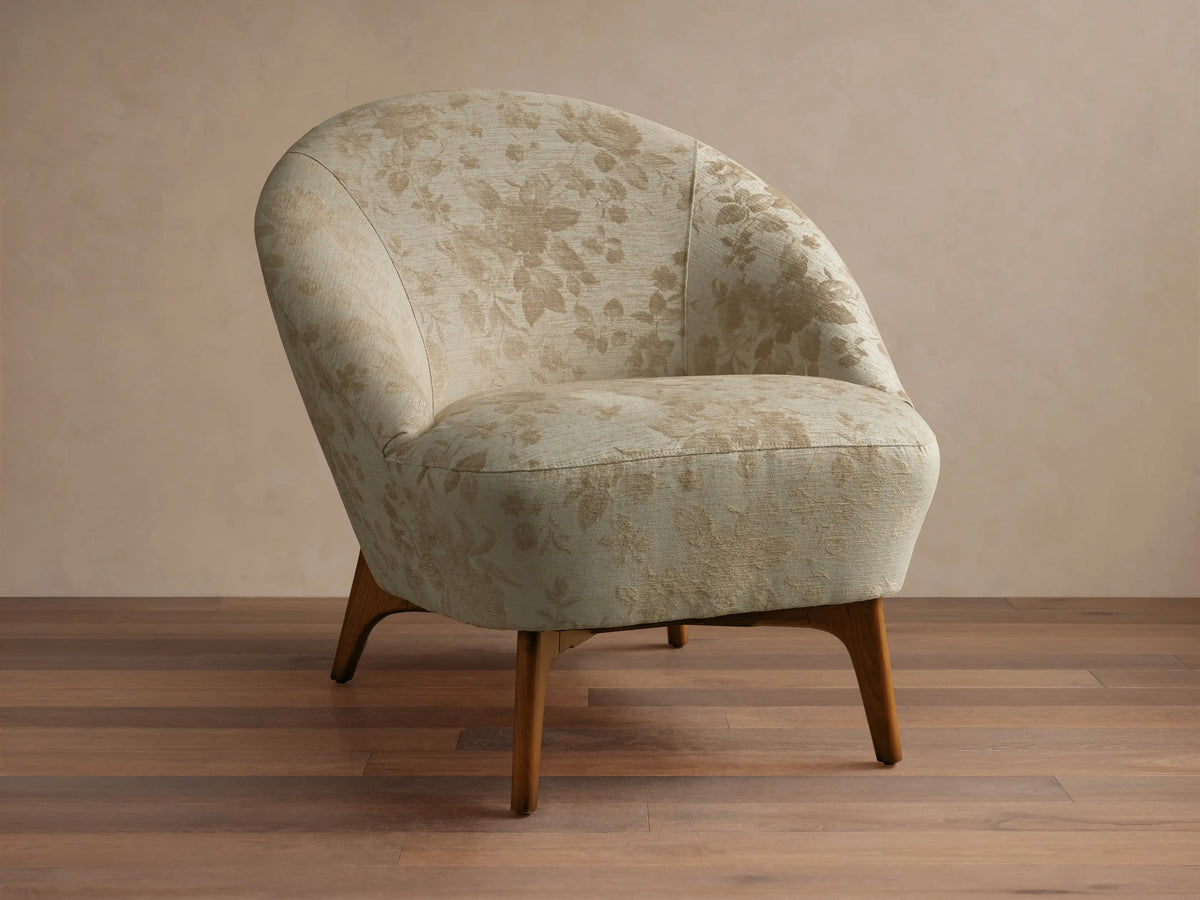 Front view of the beige floral Elodie Chair with a rounded back and tapered wooden legs.