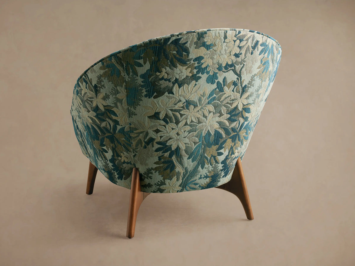 Close-up of Elodie Chair in blue, beige, and green botanical woven fabric, showing curved seat and back.