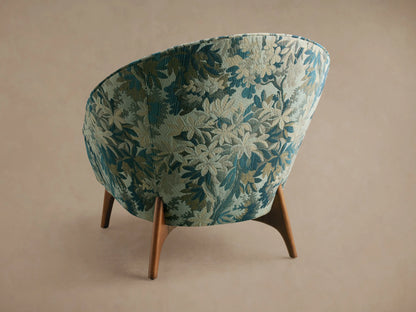 Close-up of Elodie Chair in blue, beige, and green botanical woven fabric, showing curved seat and back.