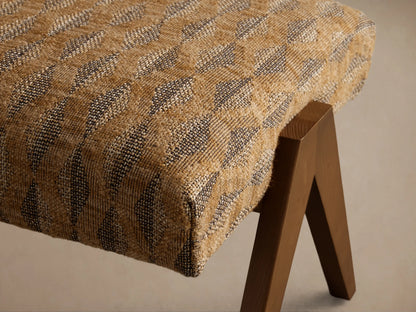 Front view of Elias Ottoman, upholstered in brown and black geometric patterned fabric with four angled wooden legs.