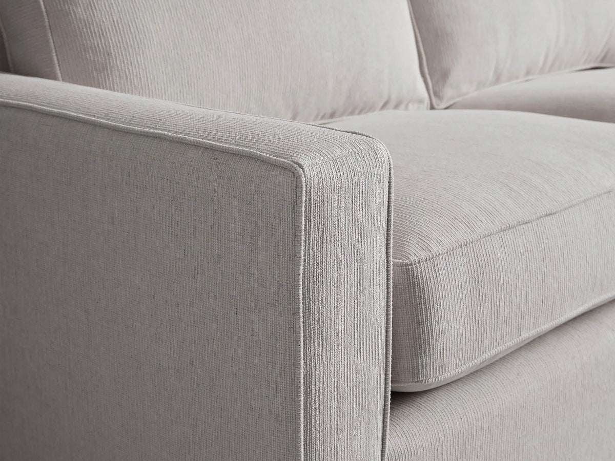 Filmore Air Sleeper Sofa, light gray heathered fabric, two seat/back cushions, square arms, on wood floor against a neutral wall.