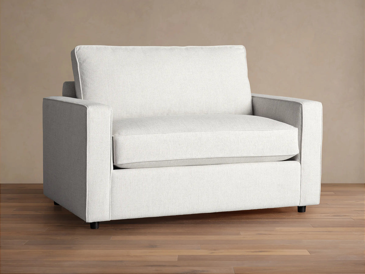 Filmore Twin Air Sleeper Chair, light gray textured fabric, front view, on wood floor against brown wall.