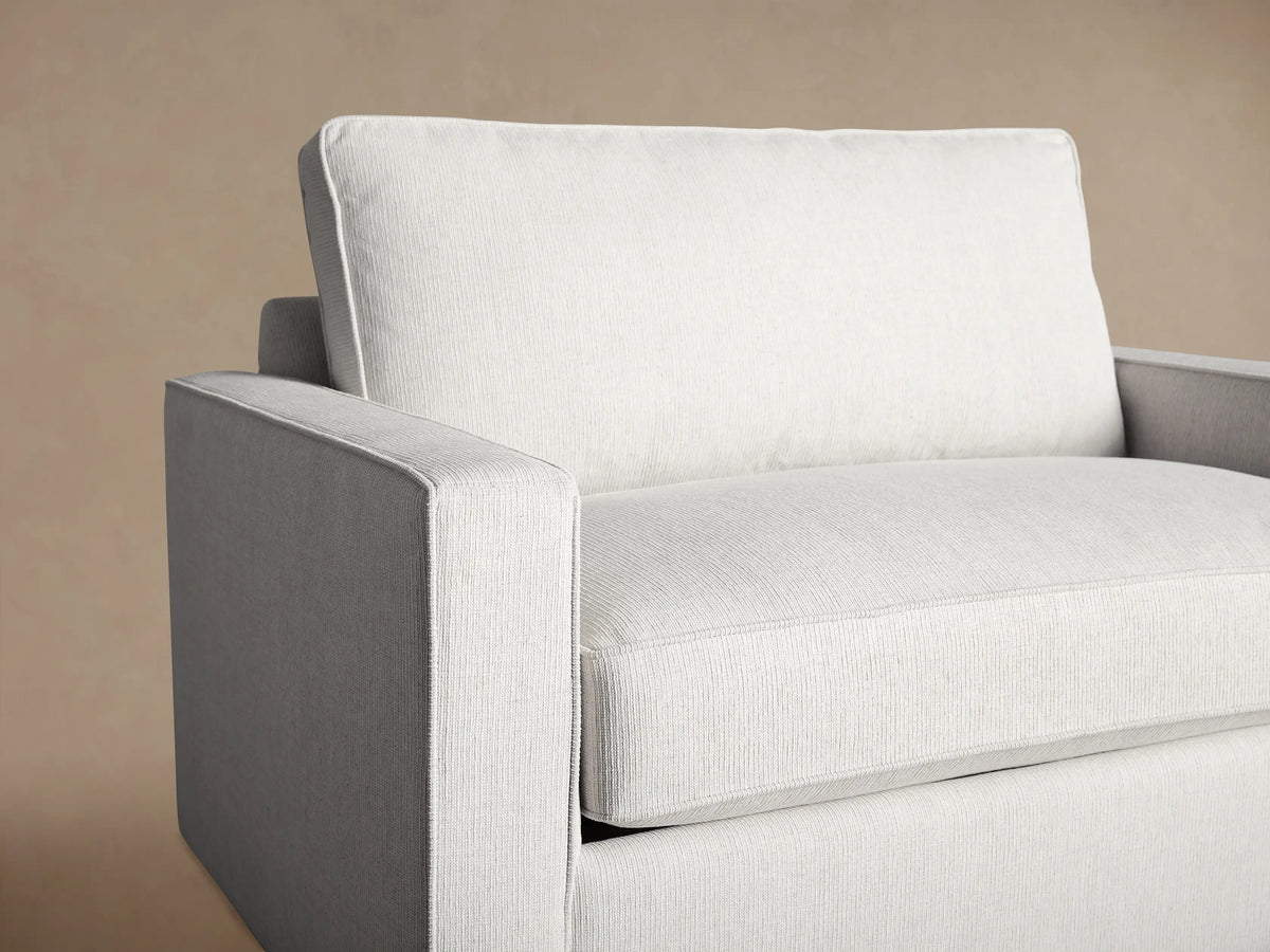 Filmore Twin Air Sleeper Chair in light gray woven fabric, front-left view, with square arms and plump cushions, on wood floor.