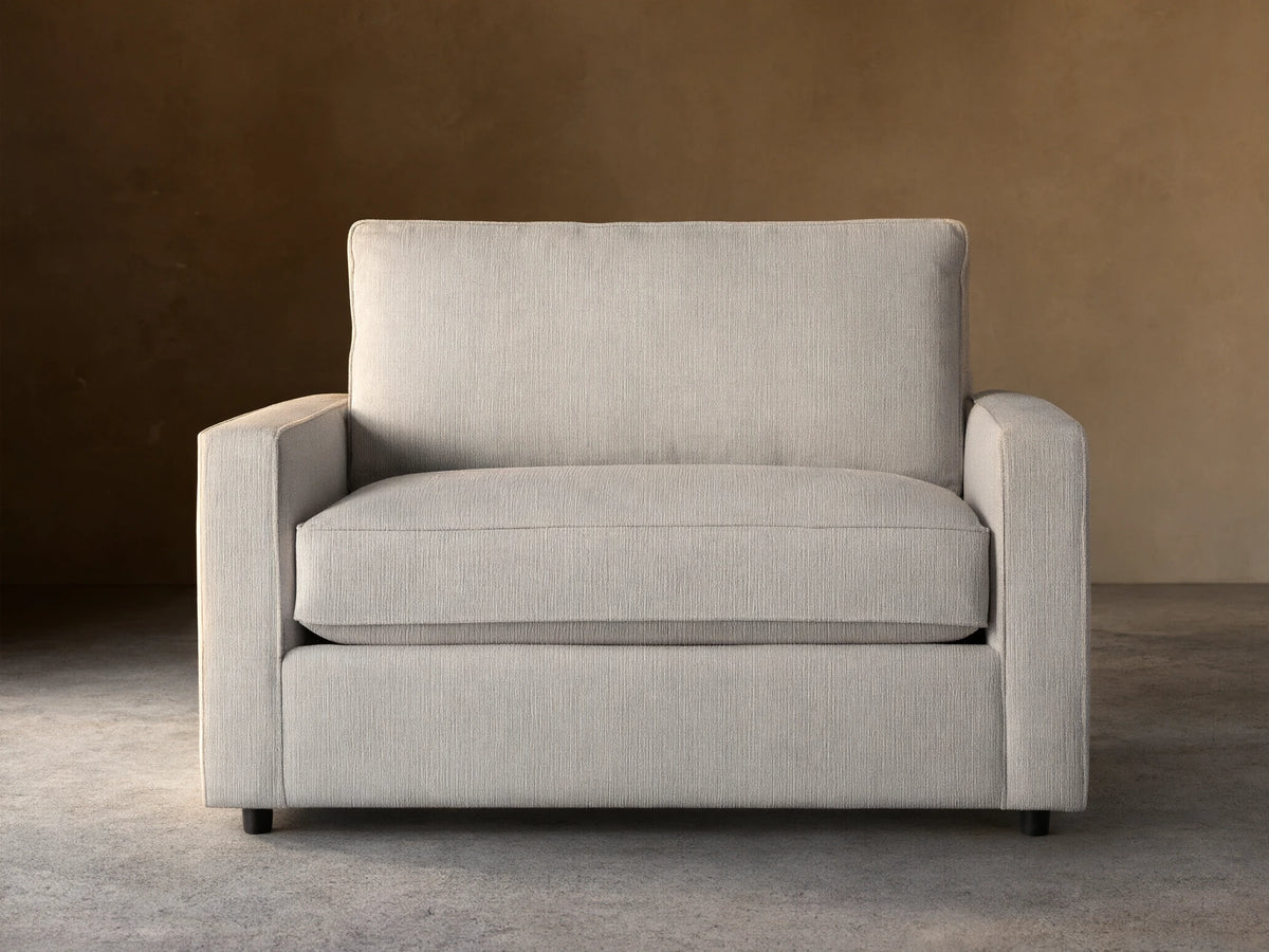 Filmore Twin Air Sleeper Chair, light gray textured fabric, front view, on wood floor against brown wall.