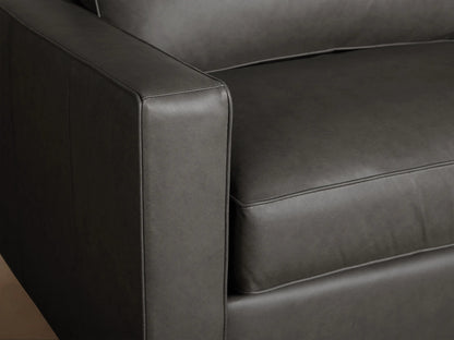 Filmore Leather Air Sleeper Sofa, grey, with two seat & back cushions, square arms, on a light wood floor.
