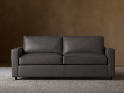 Dark gray Filmore Leather Air Sleeper Sofa, modern design with straight arms and piped cushions, against a neutral wall and wood floor.