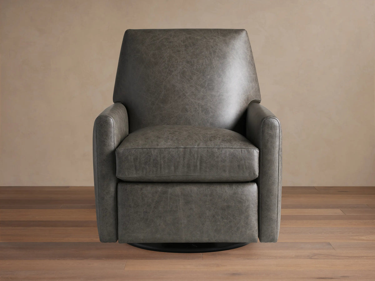 Harvey Leather Swivel Recliner in textured charcoal grey leather, front-right view, on a wooden floor against a beige wall.