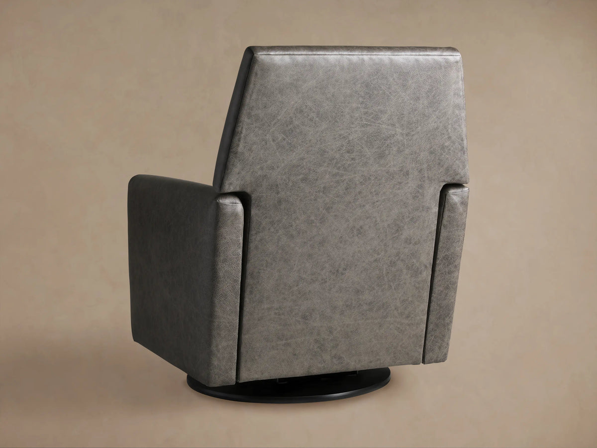 Close-up of the Harvey Leather Swivel Recliner, showing its textured dark grey leather backrest and armrest against a beige wall.