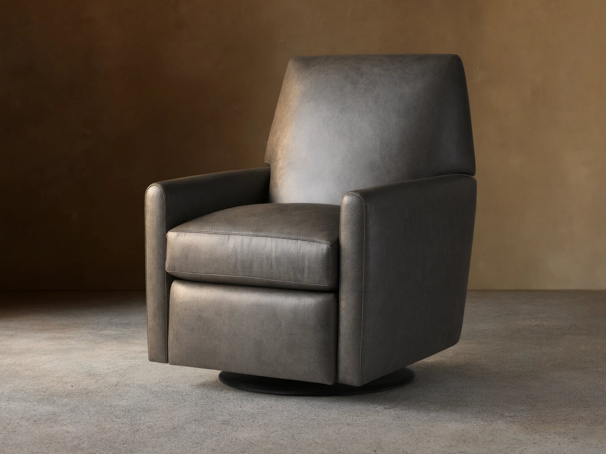 Harvey Leather Swivel Recliner in textured charcoal grey leather, front-right view, on a wooden floor against a beige wall.