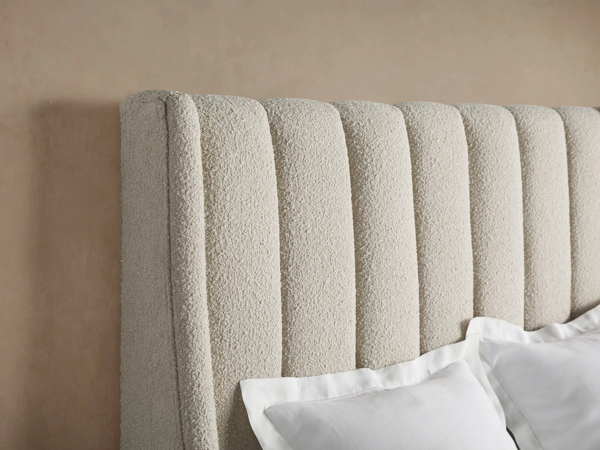 Hayworth Bed, full view. Beige textured upholstered bed with a tall, channel-tufted headboard, white duvet and pillows.