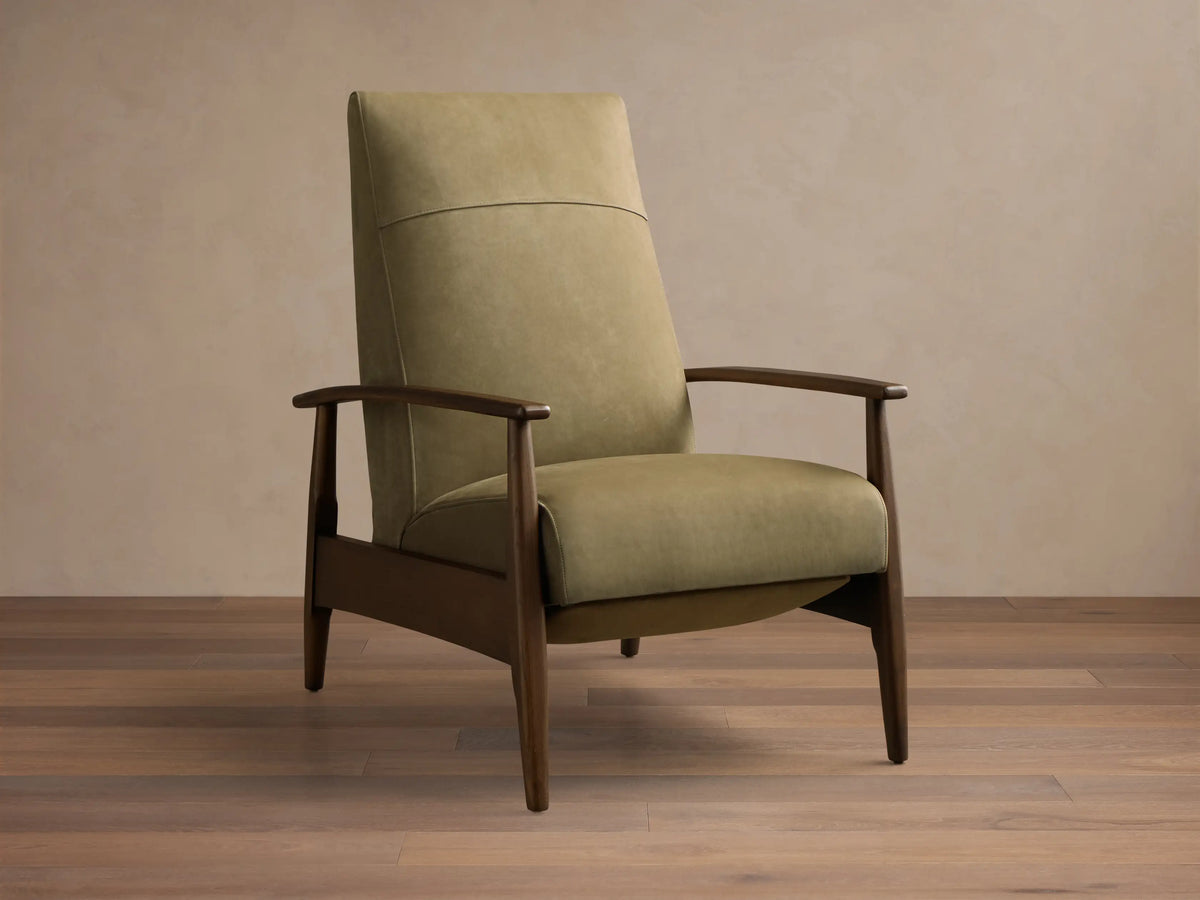 Front view of a sage green upholstered armchair with a horizontal back seam, dark wood armrests, and tapered legs.