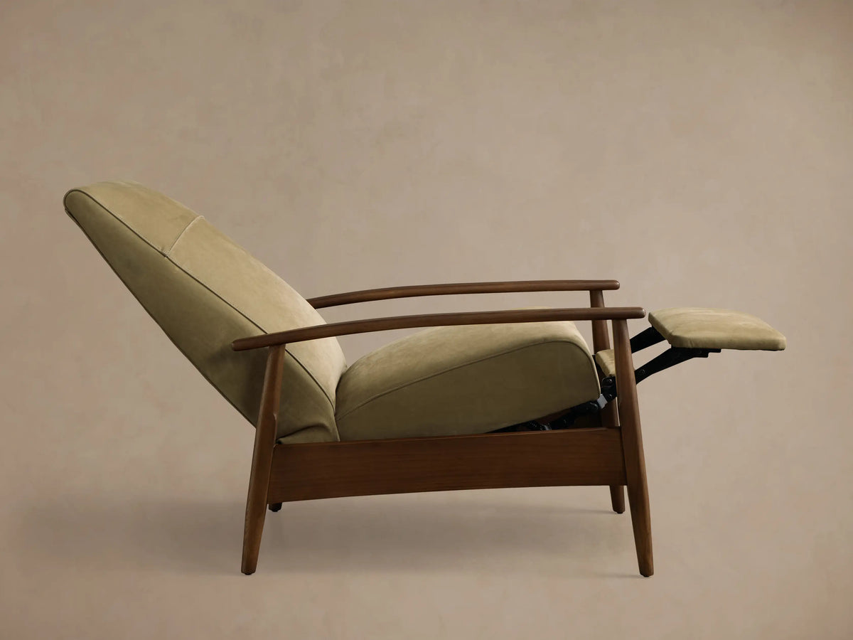 Front view of a sage green upholstered armchair with a horizontal back seam, dark wood armrests, and tapered legs.