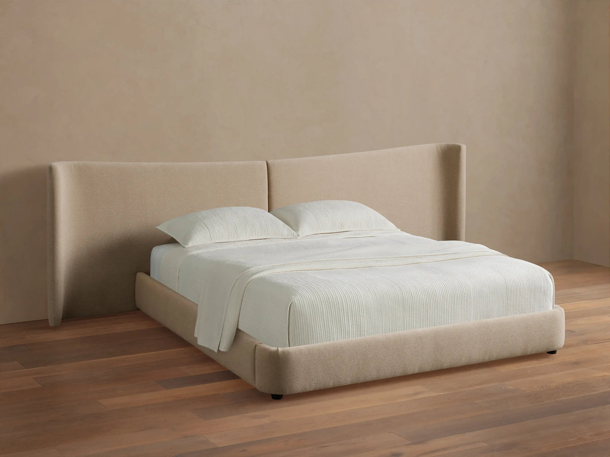 Hathaway Extended Bed: Light beige upholstered platform bed with extended winged headboard and white striped bedding.