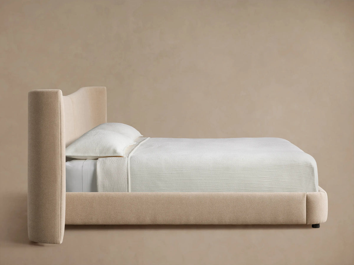 Hathaway Extended Bed: Close-up of curved, padded headboard edge in soft, textured light beige fabric.