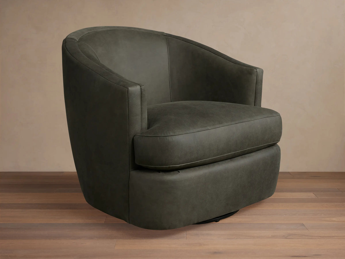 Kieran Leather Swivel Chair in dark gray, featuring a curved back, round seat, and smooth finish on wooden floor.