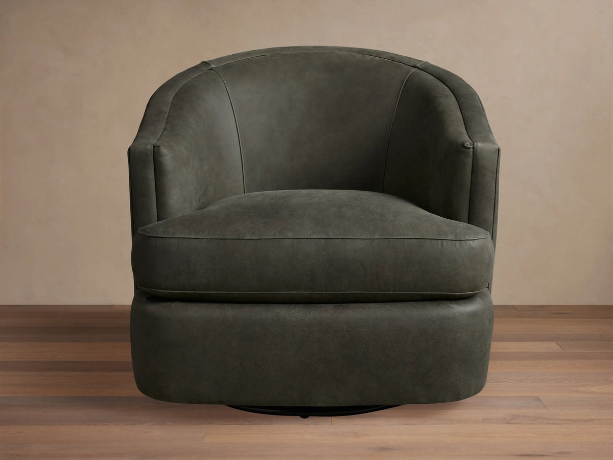 Kieran Leather Swivel Chair in dark gray, featuring a curved back, round seat, and smooth finish on wooden floor.