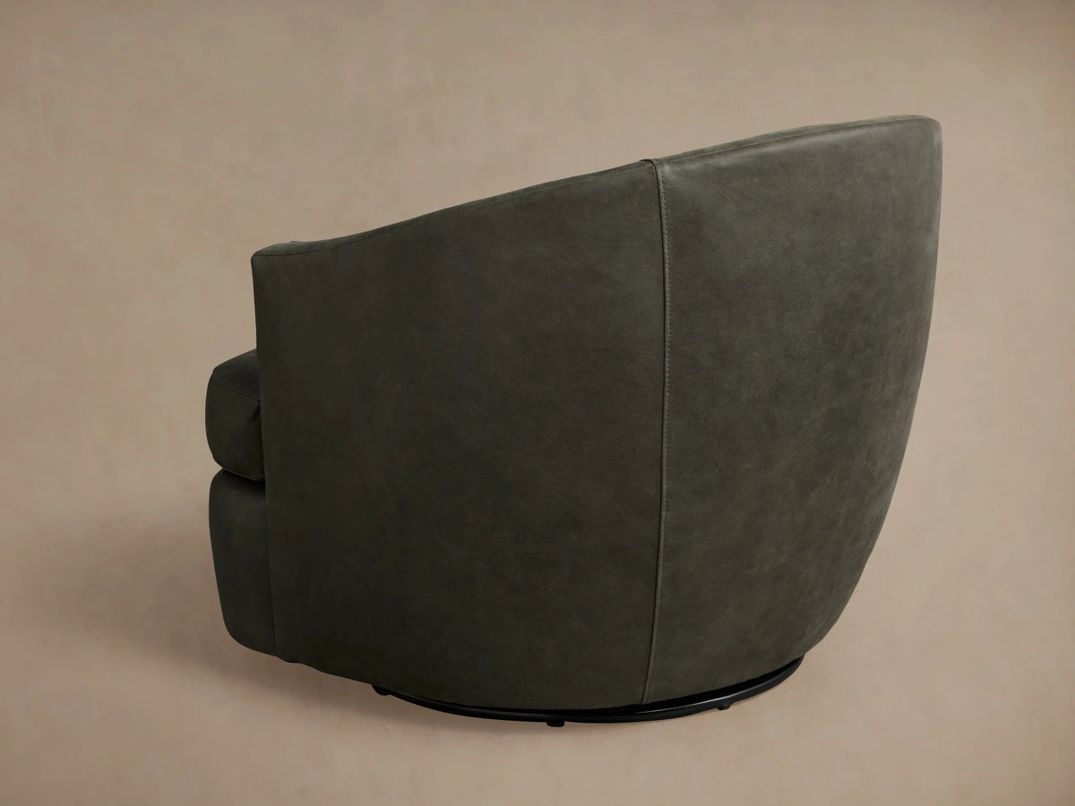 Kieran Leather Swivel Chair in dark gray, side view, showcasing smooth leather upholstery and a curved, modern design on a beige background.