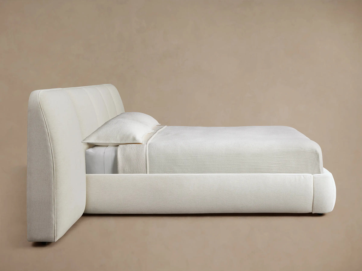 Cream-colored upholstered headboard with soft vertical padding, displayed against a light brown wall for a cozy bedroom feel.