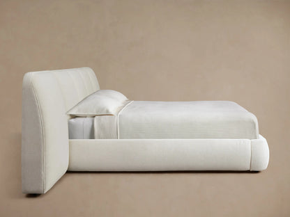 Cream-colored upholstered headboard with soft vertical padding, displayed against a light brown wall for a cozy bedroom feel.