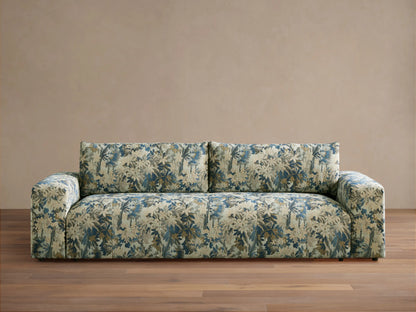 Keegan Sofa in a blue, cream, and brown botanical pattern, featuring wide arms and soft cushions, on a wooden floor.