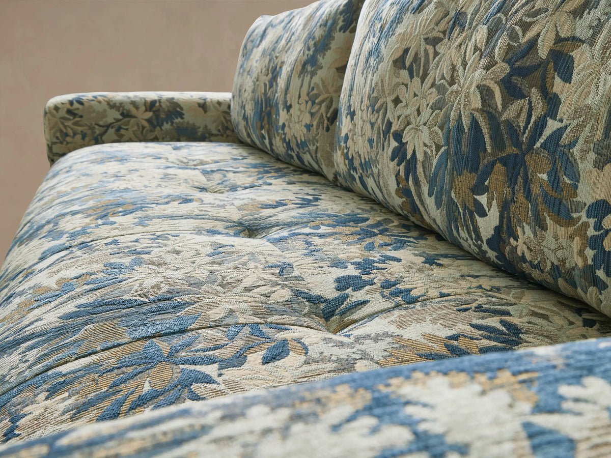 Keegan Sofa, front view. Blue, green, and cream botanical pattern covers the rectangular sofa with thick arms on a wood floor.