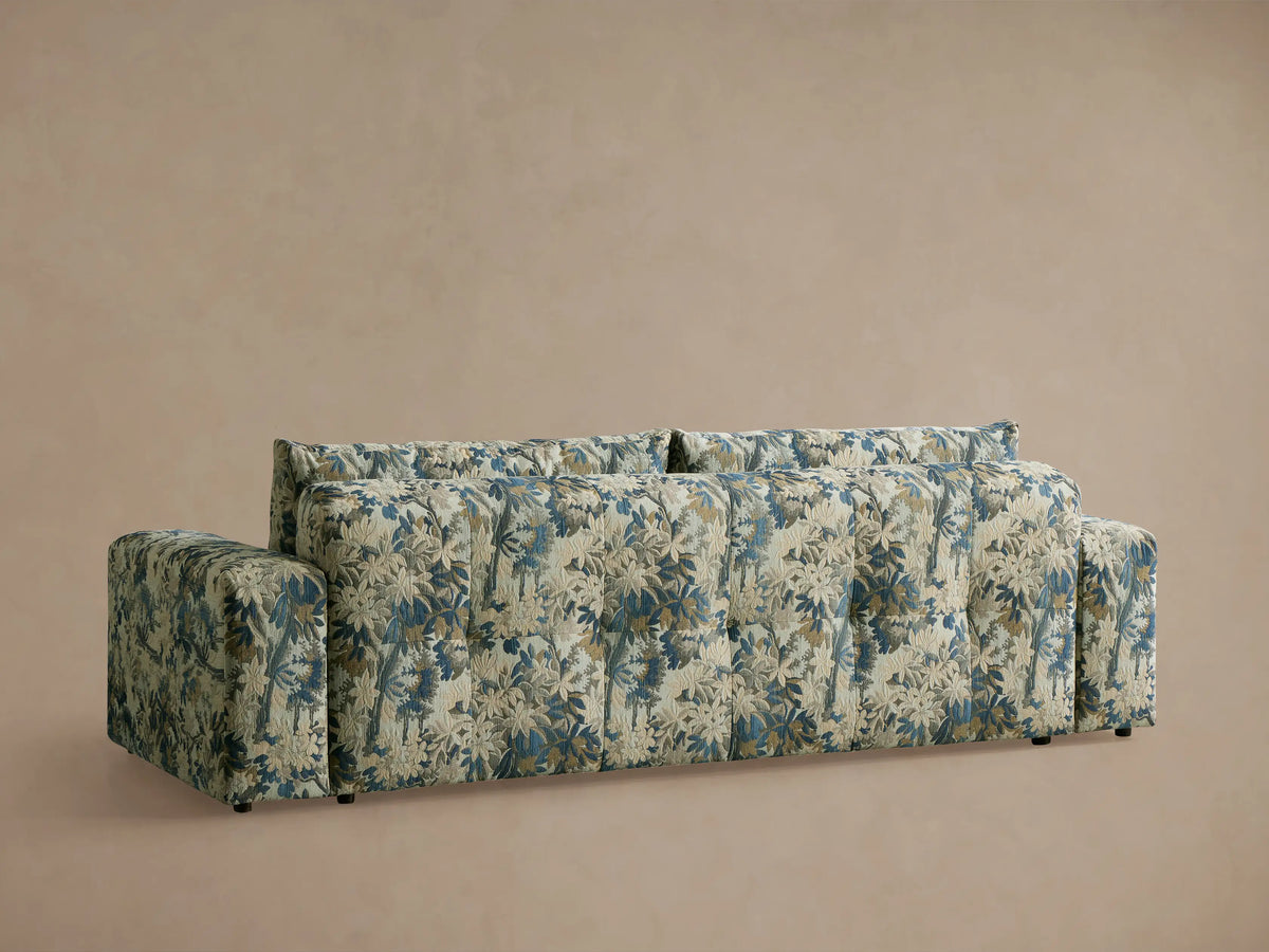 Close-up angled view of Keegan Sofa. Tufted seat, back & armrest in blue, beige, cream intricate floral tapestry fabric.