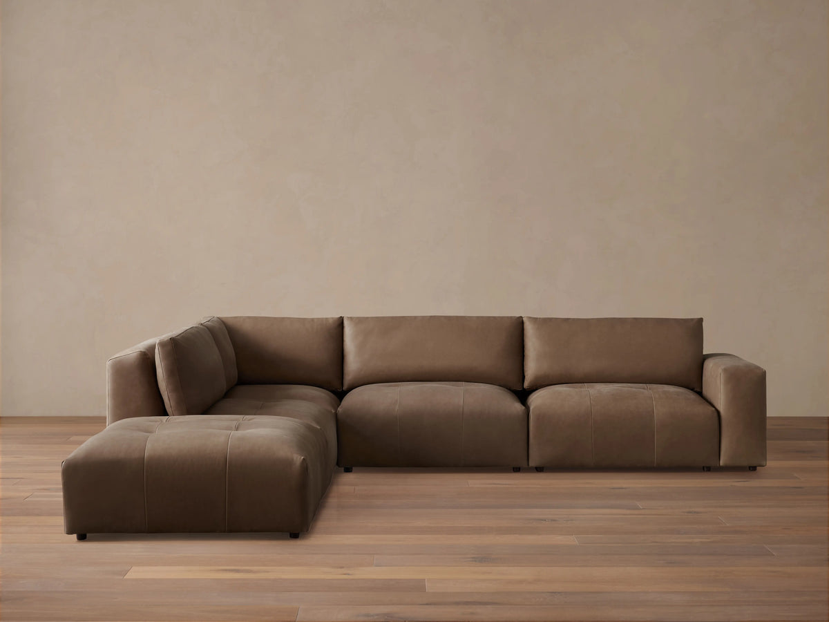 Keegan Leather Five-Piece Sectional in brown leather, L-shaped, with cushiony seat and backrest on wooden floor against a neutral wall.