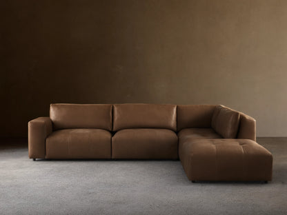 Keegan Leather Five-Piece Sectional in brown leather, L-shaped, with cushiony seat and backrest on wooden floor against a neutral wall.