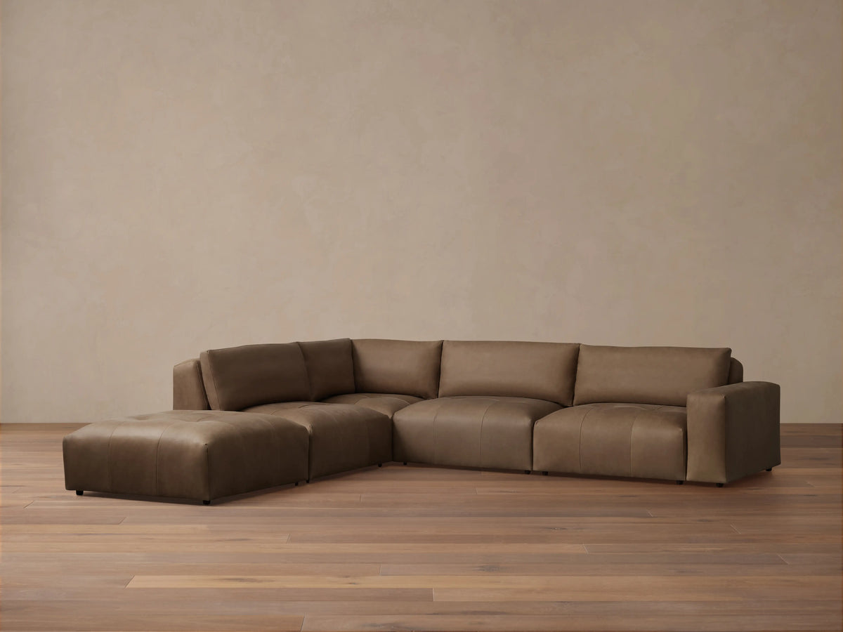 Keegan Leather Five-Piece Sectional in brown leather, L-shaped, with cushiony seat and backrest on wooden floor against a neutral wall.
