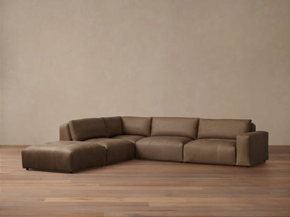 Keegan Leather Five-Piece Sectional in brown leather, L-shaped, with cushiony seat and backrest on wooden floor against a neutral wall.
