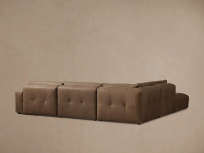 Keegan Leather Sectional in brown leather, showcasing a plush, tufted seat cushion with visible stitching and padded armrest.