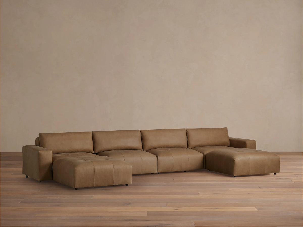 Brown leather Keegan six-piece sectional on wooden floor against beige wall, featuring clean lines and plush cushions.